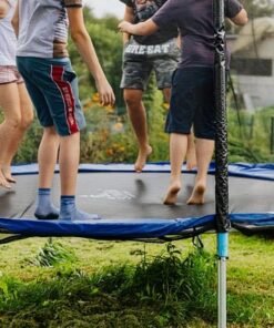 Enfants sautant sur un trampoline rond avec filet de protection, activité ludique proche d’un trampoline park.
